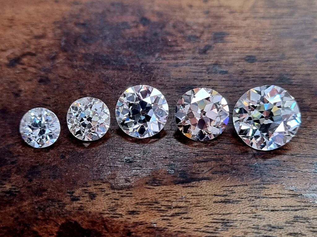 5 old european cut diamonds next to each other on a wooden background