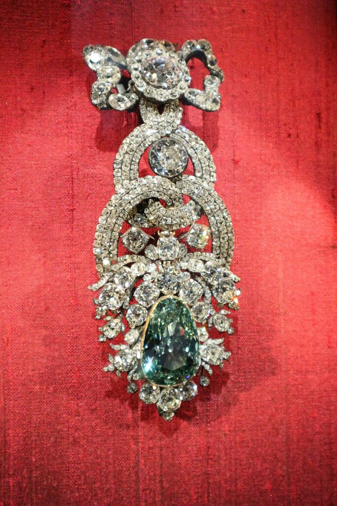 Dresden Green Diamond in hat clasp ornament on a red venlvet background