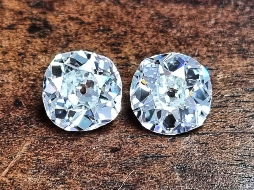 a pair old old mine cut diamonds on a wooden backgroung