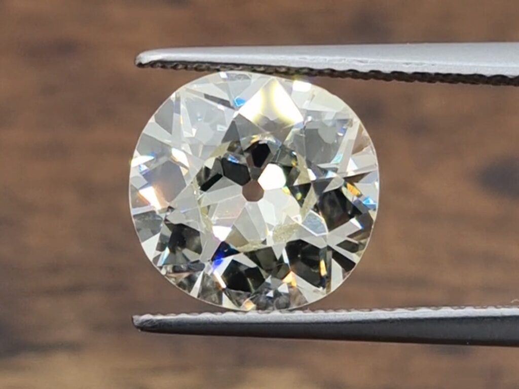 A 2.50ct old european cut diamond held in a tweezer on a wooden background