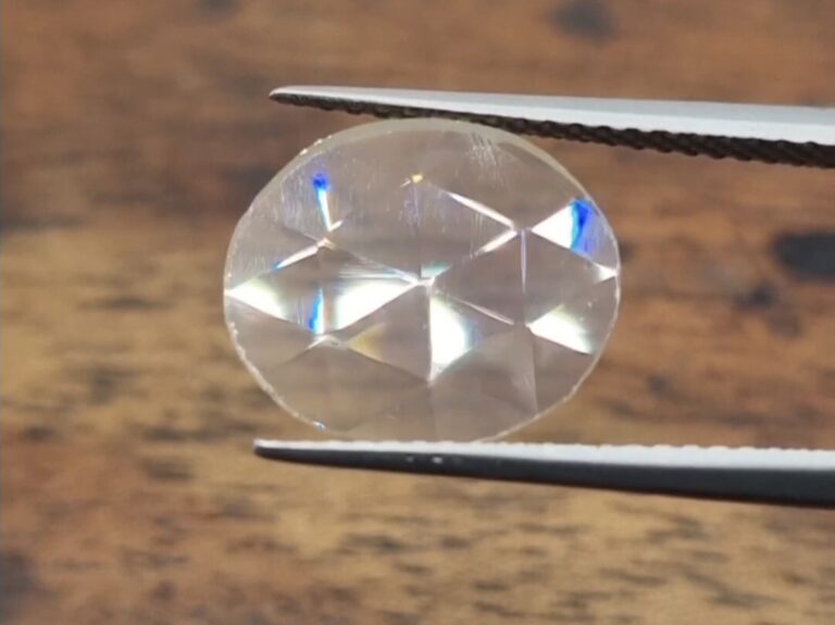 antique rose cut diamond held in a tweezer on a wooden background