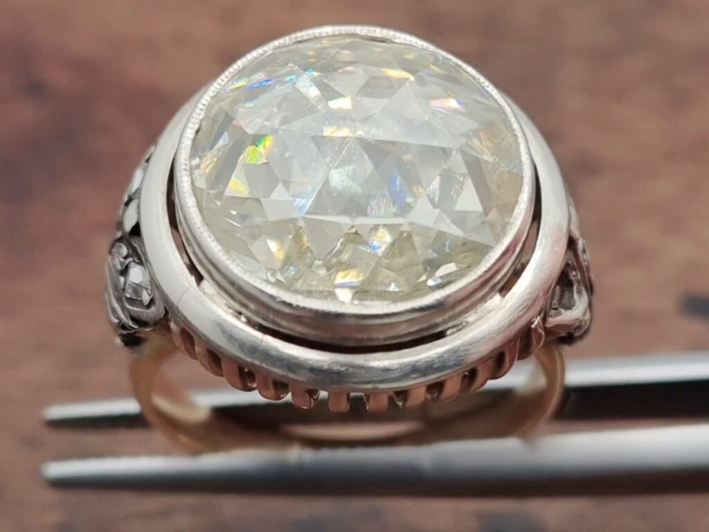 diamond ring with a Persian Rose Cut diamond being held in a tweezer on a wooden background