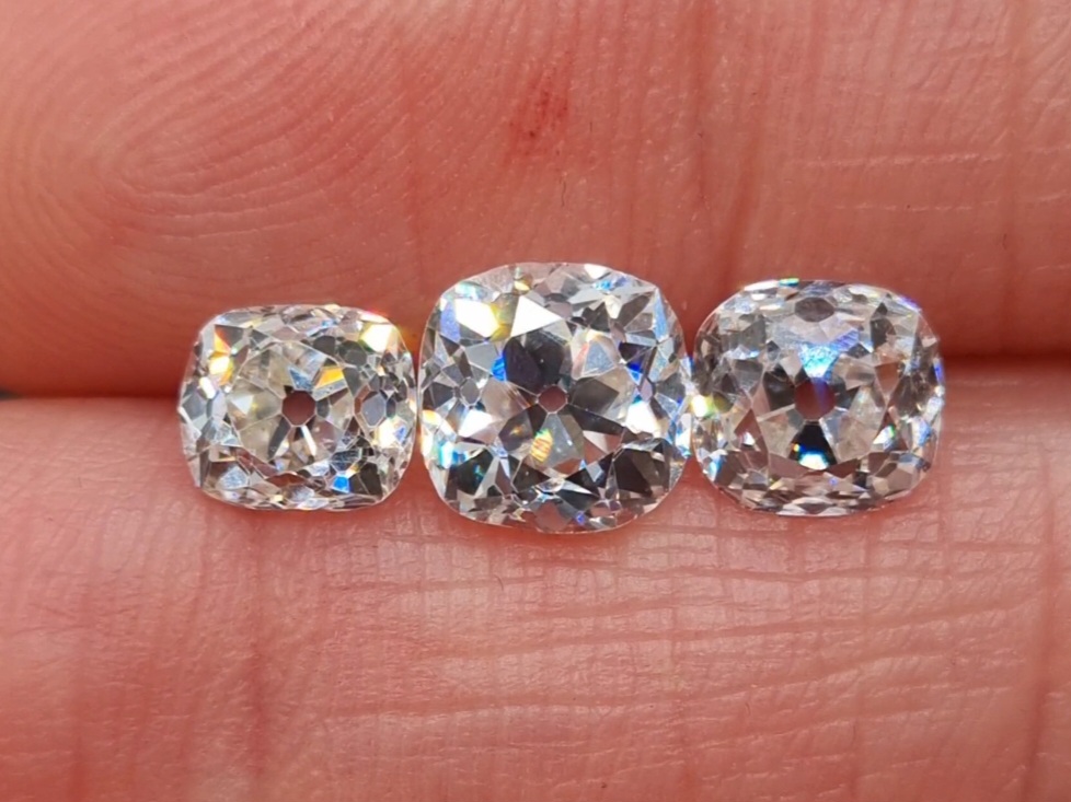 3 old mine cut diamonds held between fingers